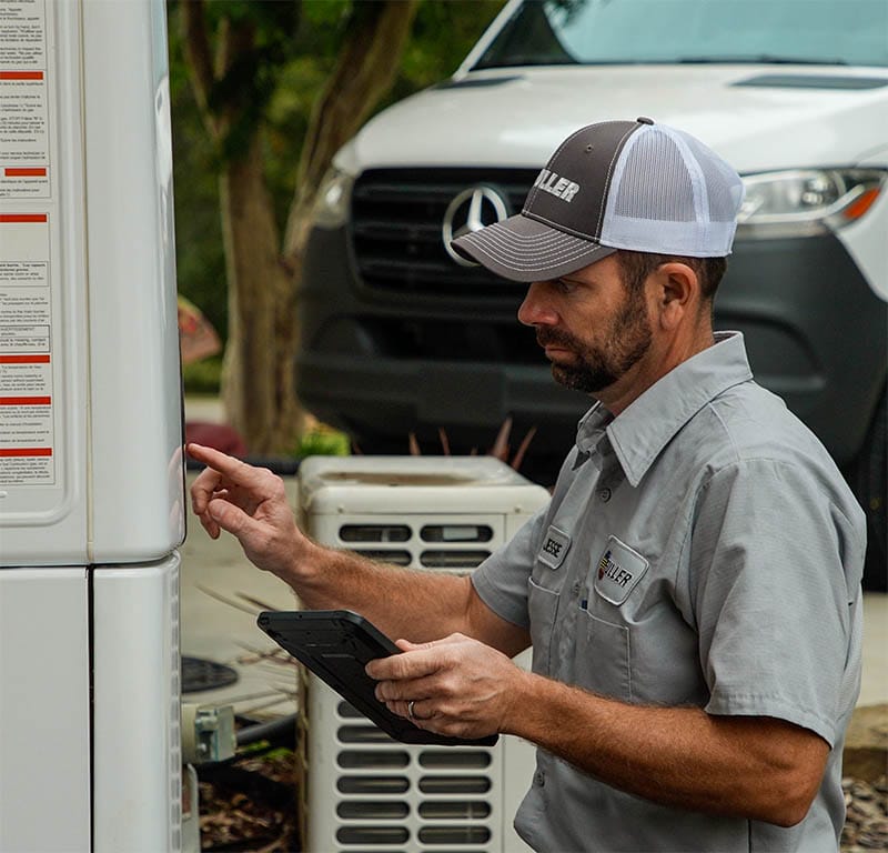 Fuller technician walking with tools in front of a multicolor HVAC service van.