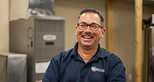 Smiling Fuller HVAC expert standing confidently inside a heating and cooling workshop.