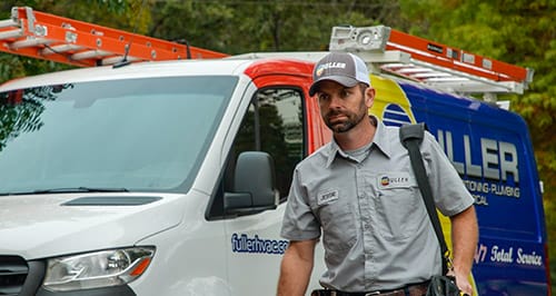 Fuller HVAC field technician approaching a job site with tools in front of a branded HVAC service van.