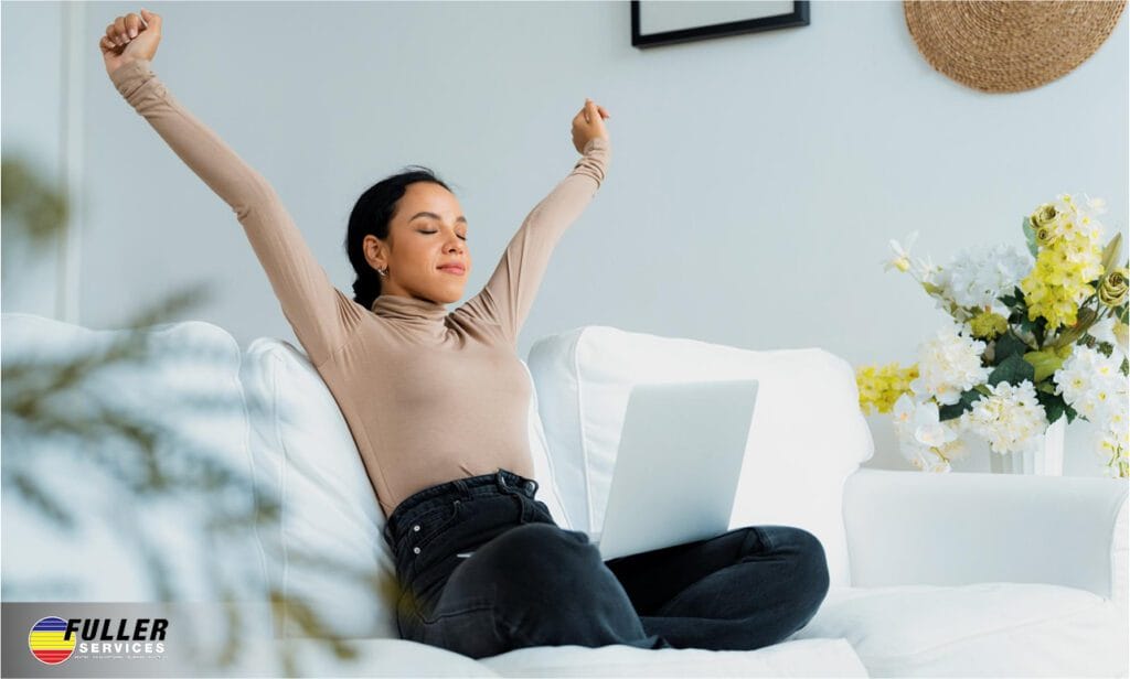 Woman relaxing comfortably on a couch with a laptop, representing improved comfort and relief from allergies through clean indoor air and an efficient HVAC system