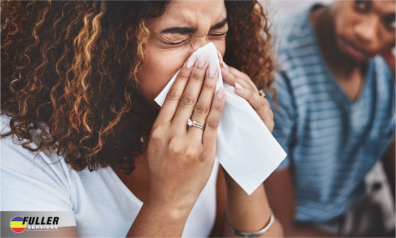 Person sneezing into a tissue indoors, highlighting allergy symptoms linked to poor indoor air quality and HVAC filtration