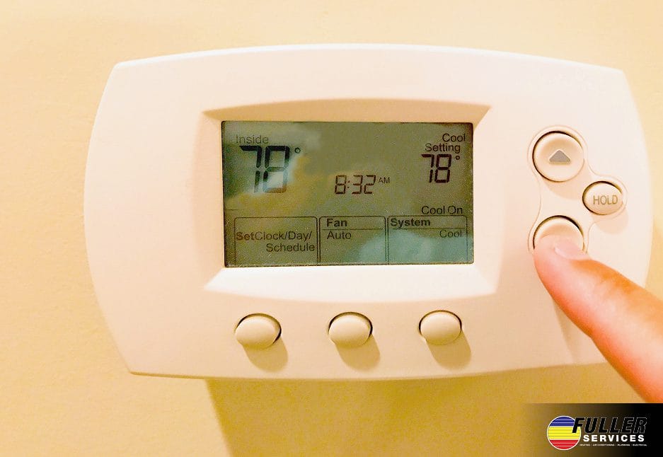 Man adjusting a wall-mounted thermostat to control indoor temperature for energy efficiency and comfort.