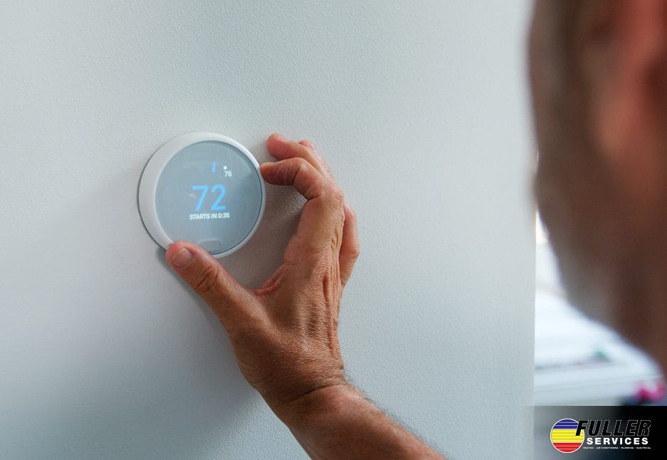 Person adjusting smart thermostat to energy-efficient temperature for better sleep and energy savings.